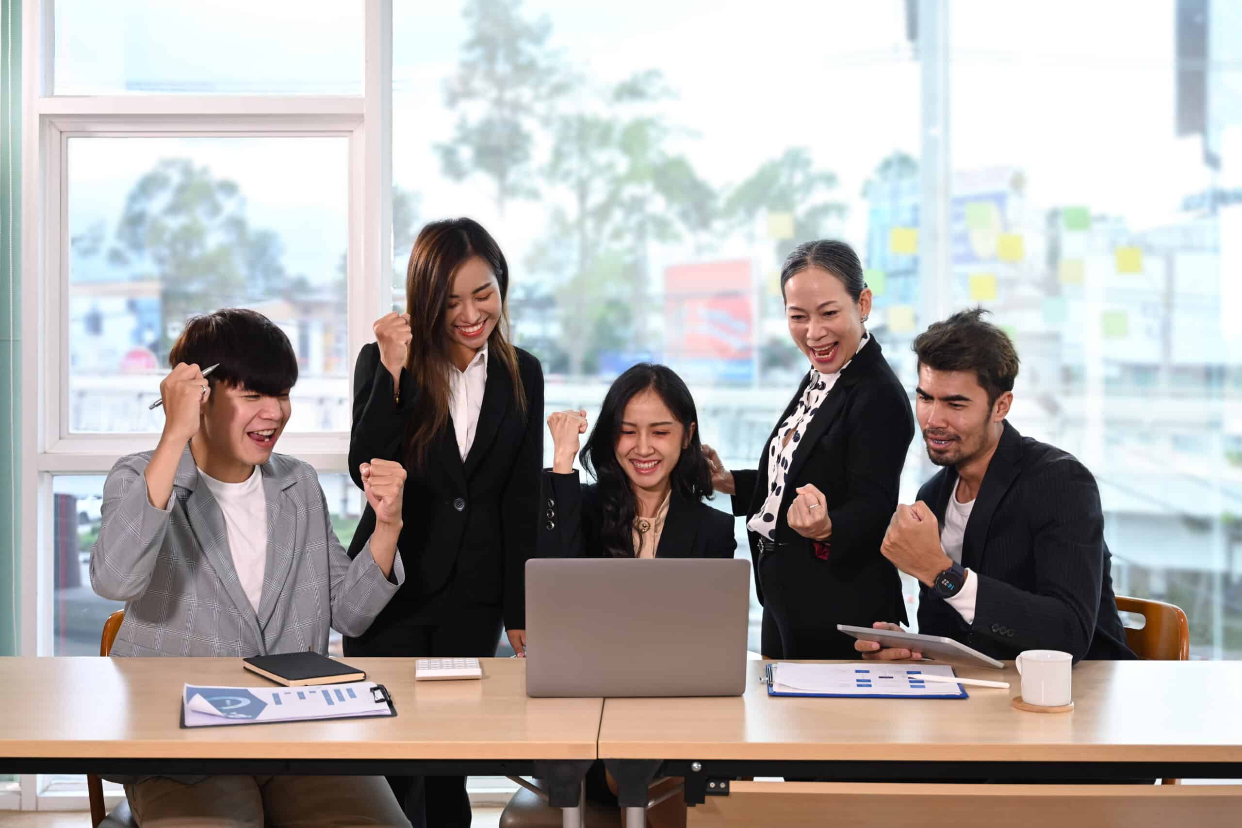 Diverse employees celebrating business success or victory together in office.