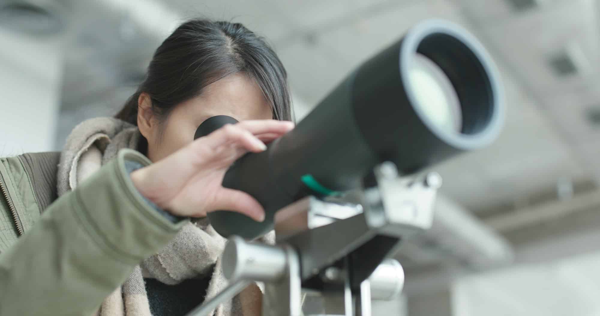 Woman looking through telescope to observe the bird